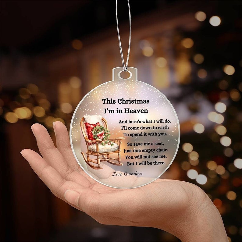 May include: Clear Christmas ornament with the text "This Christmas I'm in Heaven" and a poem. The ornament features a rocking chair with a Christmas stocking and wreath. A silver string is attached for hanging.