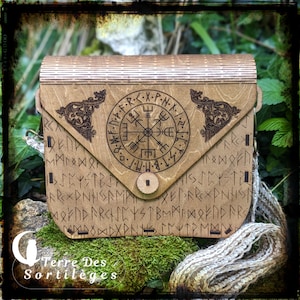 Peut inclure: Une boîte en bois avec un motif de boussole et des runes gravées sur le devant. La boîte a un rabat qui s'ouvre et se ferme. La boîte est en bois brun clair et a un aspect rustique.