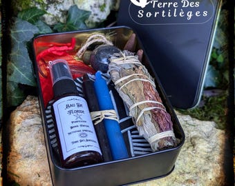 May include: A black metal box filled with spiritual items. Includes a spray bottle labeled "Eau de Floride", black and blue candles, a bundle of sage, and other ritualistic objects. The box is open, revealing the contents.