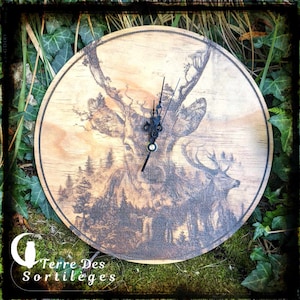 May include: A wooden clock with a black deer design and black hands. The clock is round and has a wood grain finish. The clock is on a green mossy surface.