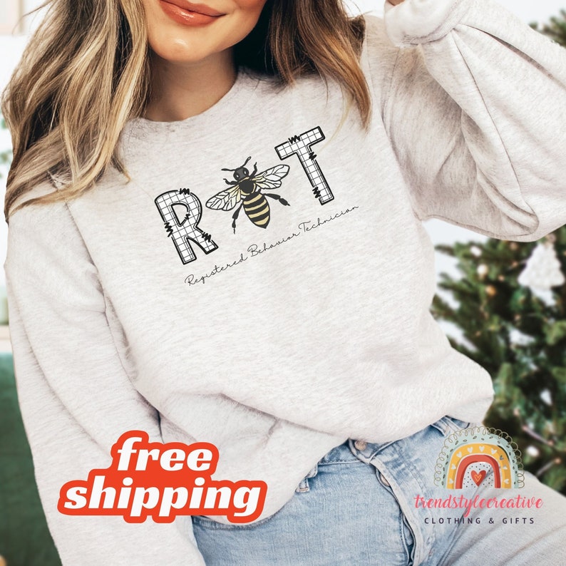 May include: A gray sweatshirt with the letters RBT in black outlined in white, with a bee in the middle of the letters. The text below the letters says "Registered Behavior Technician".