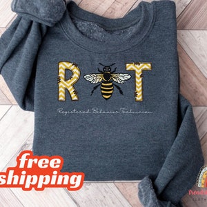 May include: A dark gray sweatshirt with the letters RBT in yellow and black with a bee in the middle. The letters are made of a yellow and black chevron pattern. The text "Registered Behavior Technician" is below the letters.