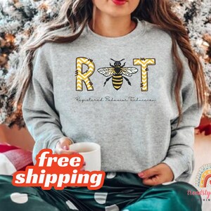 May include: Gray sweatshirt with a bee graphic and the text "RBT Registered Behavior Technician".