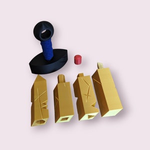 May include: A set of five 3D printed objects, including a black base with a blue top, a red cylinder, and four gold-colored pieces with intricate designs.
