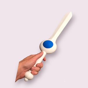 May include: A white foam sword with a blue circle on the end. The sword is being held by a hand.