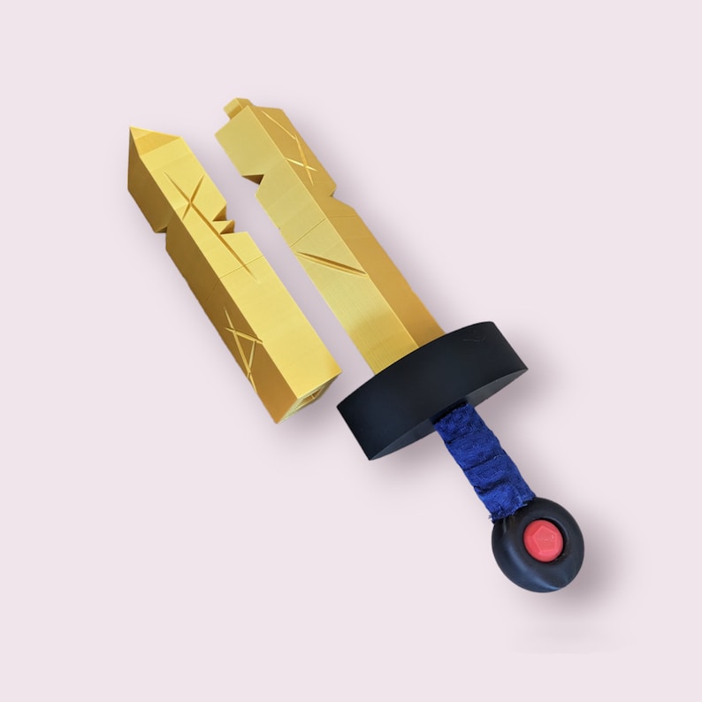May include: A gold-colored plastic sword with a blue handle and a red button. The sword is broken into two pieces.
