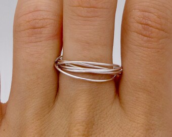 May include: A silver ring with multiple thin bands intertwined, worn on a finger.