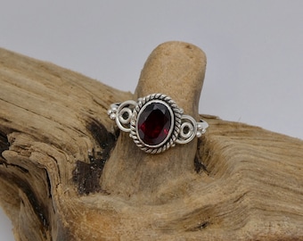 May include: A silver ring with a red gemstone set in a decorative silver setting.