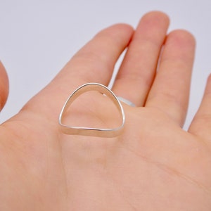 May include: A silver ring with a rounded top and a flat bottom, shaped like a half-arch. The ring is displayed on a light-colored background.