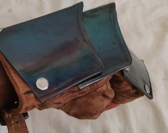 May include: A pair of brown leather fingerless gloves with metal knuckle guards. The guards have a blue and green iridescent finish.