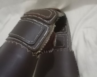 May include: A pair of brown leather fingerless gloves with white stitching. The gloves have a reinforced palm and fingertip area.