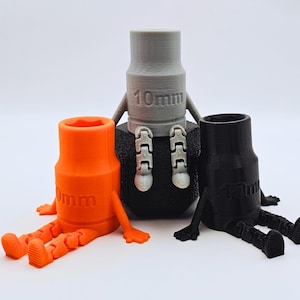 May include: Three 3D-printed socket-shaped figures in orange, gray, and black. Each figure features a cylindrical body with the text 10mm embossed on the front, articulated arms, and jointed legs that allow them to sit in a seated position.