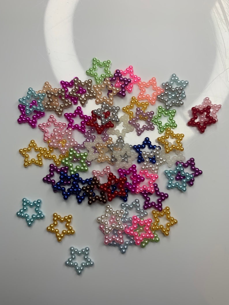 May include: A collection of colorful pearl star-shaped embellishments. The stars are made of small pearls in various colors, including pink, blue, green, purple, red, and gold.