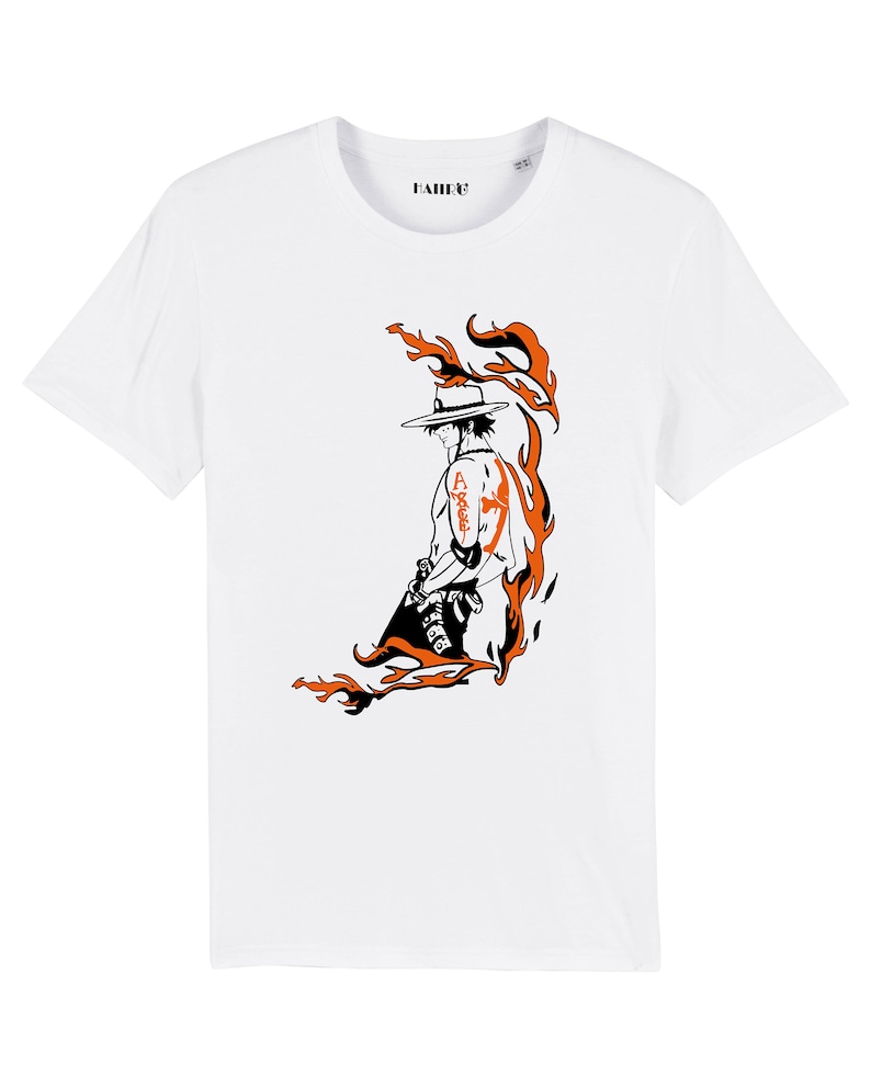 May include: White t-shirt with a black and orange illustration of a character with a straw hat and flames behind them. The character has a tattoo on their arm that says "Ace".