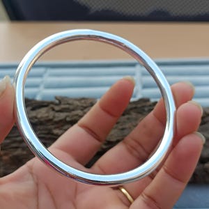 May include: A silver bangle bracelet with a smooth, polished finish.