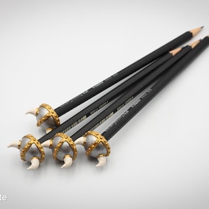 May include: Four black pencils with gold and silver Viking helmet-shaped erasers. The erasers have white horns.