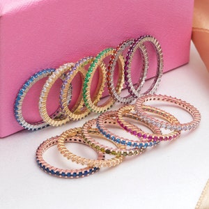 May include: A set of ten thin gold rings with colorful gemstones. Each ring is set with a single row of small gemstones.