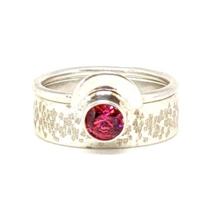 Peut inclure: Une bague en argent avec une bande texturée et une pierre précieuse rose sertie dans un sertissage incurvé en argent.