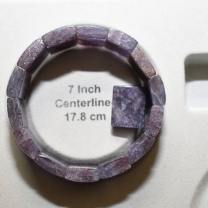Puede incluir: Un brazalete de piedras preciosas de color p&uacute;rpura y gris con una circunferencia de 17,8 cm. El brazalete est&aacute; hecho de piedras rectangulares individuales.
