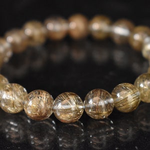 May include: A gold and clear crystal bracelet with a beaded design. The beads are round and have a translucent appearance with gold flecks throughout.