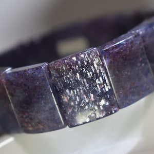 Puede incluir: Un brazalete morado y plateado hecho de cuentas rectangulares de piedras preciosas.