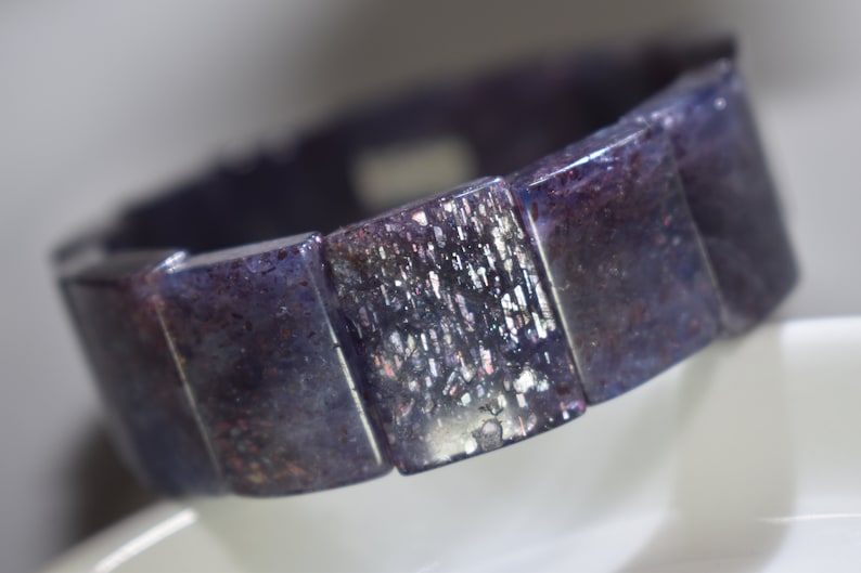 Puede incluir: Un brazalete morado y plateado hecho de cuentas rectangulares de piedras preciosas.