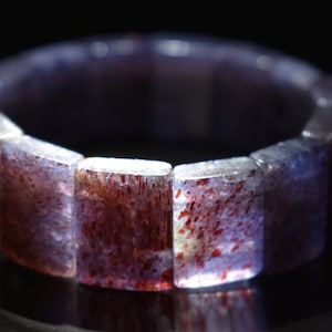 Puede incluir: Un brazalete de piedras preciosas de color p&uacute;rpura y rojo hecho de cuentas rectangulares.