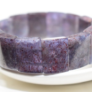 Puede incluir: Un brazalete de piedras preciosas de color p&uacute;rpura y rojo hecho de cuentas rectangulares.