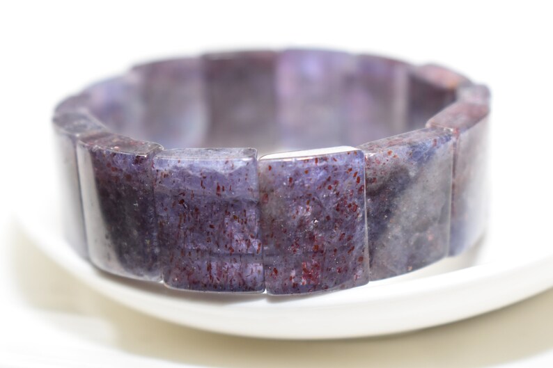 Puede incluir: Un brazalete de piedras preciosas de color p&uacute;rpura y rojo hecho de cuentas rectangulares.