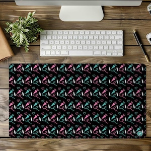 May include: Black desk mat with a repeating pattern of pink and blue headphones with hearts.