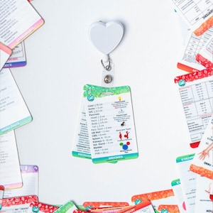 May include: A set of colorful flashcards with medical illustrations and text. The cards are organized by body system and include information about anatomy, measurements, and conditions. The cards are attached to a white heart-shaped retractable badge holder.