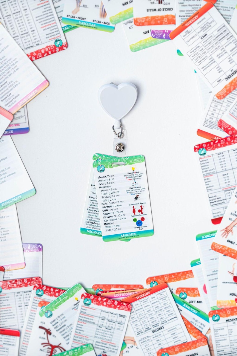May include: A set of colorful flashcards with medical illustrations and text. The cards are organized by body system and include information about anatomy, measurements, and conditions. The cards are attached to a white heart-shaped retractable badge holder.