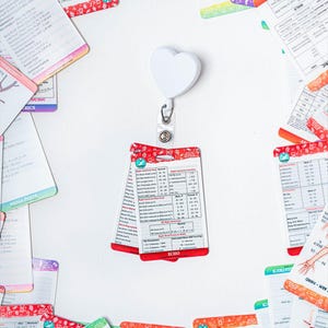 May include: A white heart-shaped retractable badge holder with a red and white card attached. The card has a table with medical information about the right ventricle. The card is labeled "ECHO".