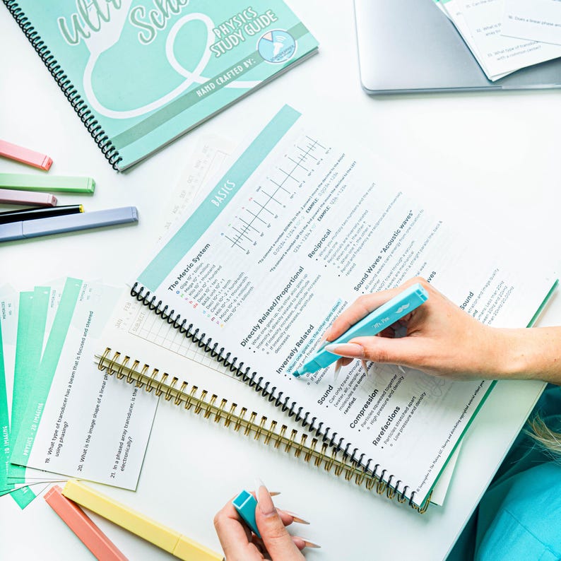 Pode incluir: Um caderno espiral azul-turquesa com as palavras "Physics Study Guide" e "Basics" impressas na capa. Uma m&atilde;o est&aacute; segurando um marca-texto azul-turquesa e destacando texto no caderno. O caderno est&aacute; aberto em uma p&aacute;gina com uma tabela e texto sobre ondas sonoras.