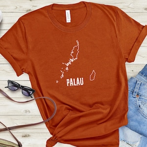 May include: A rust-coloured t-shirt with a white outline of the islands of Palau and the word "PALAU" in white text.