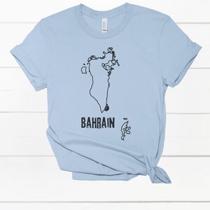 May include: Light blue t-shirt with a black outline of the country of Bahrain and the word "BAHRAIN" printed on the front.