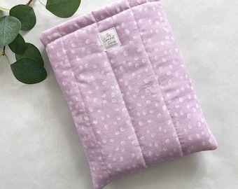 May include: A lavender quilted fabric pouch with a white polka dot pattern. The pouch has a small white label with the text "The Cuddliest Things" on it.