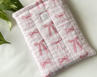 Funda protectora acolchada de forro polar para libros de bolsillo con estampado de lazo rosa.
