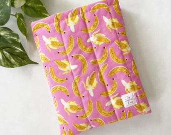 Funda acolchada para libros de bolsillo con estampado de plátanos.