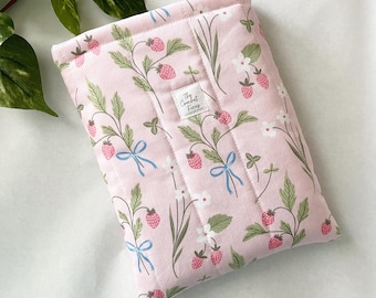 Funda protectora acolchada para libros de bolsillo con fresas rosas y lazos azules.