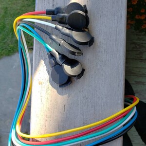 May include: A set of seven colorful wires with black connectors at the ends. The wires are yellow, red, green, white, blue, black, and turquoise.