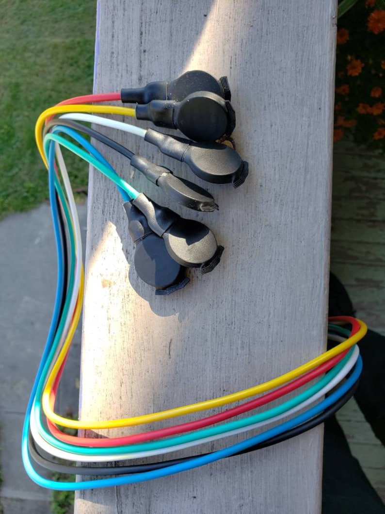 May include: A set of seven colorful wires with black connectors at the ends. The wires are yellow, red, green, white, blue, black, and turquoise.