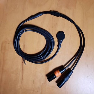 May include: Black cable with two black XLR connectors and a black microphone connector with an orange ring.