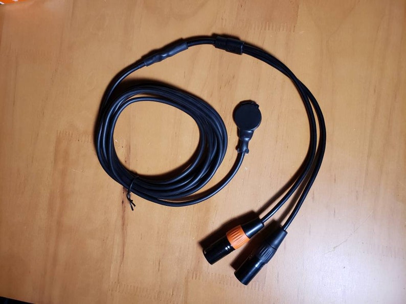 May include: Black cable with two black XLR connectors and a black microphone connector with an orange ring.