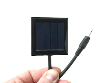 May include: A small black solar panel with a black wire and a connector. The panel is about 2 inches wide and 2 inches tall.