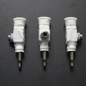 Pode incluir: Tr&ecirc;s adaptadores de &aacute;udio de cer&acirc;mica branca com pontas de metal prateadas. Os adaptadores t&ecirc;m uma extremidade rosqueada e um pequeno furo no centro.