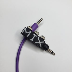 May include: A black audio splitter with the word "MIX" written in white on the side. The splitter has three inputs and one output. A purple cable is connected to the splitter.