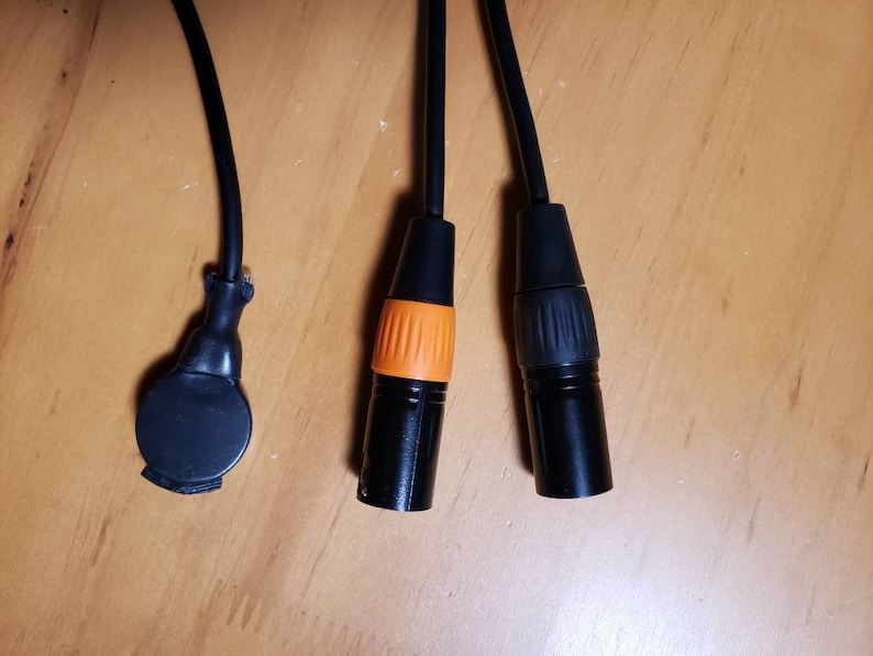 May include: Three black cables with different connectors. One connector is round and black, another is black with an orange ring, and the third is black with a gray ring.