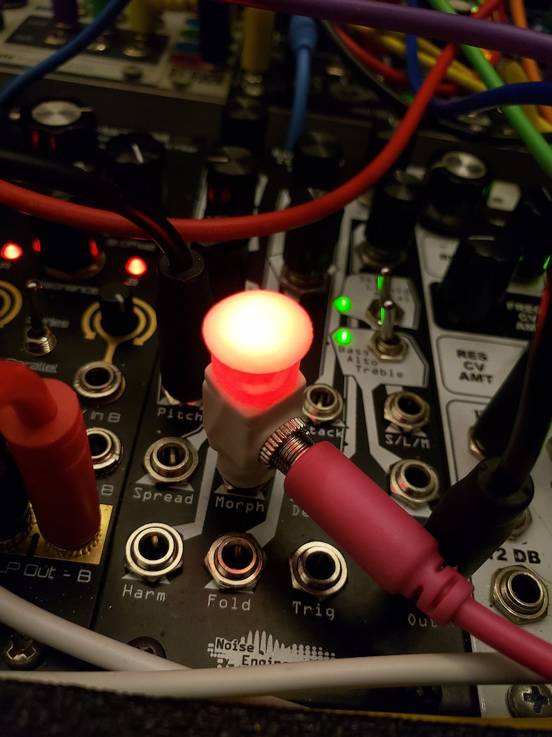 Pode incluir: Close-up de um m&oacute;dulo de sintetizador com uma luz LED vermelha acesa. O m&oacute;dulo tem bot&otilde;es rotulados como "Pitch", "Spread", "Morph", "Harm", "Fold" e "Trig". Tamb&eacute;m existem conectores rotulados como "In B", "Out" e "2 DB".
