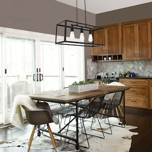 May include: A dining room with a rustic wooden table, metal chairs, and a black rectangular light fixture with three exposed bulbs. The room features wooden cabinets, a cowhide rug, and a sliding glass door.